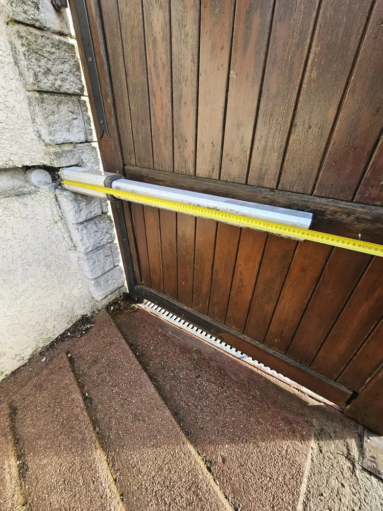 Mesure au mètre sous un vantail en bois, au-dessus des marches