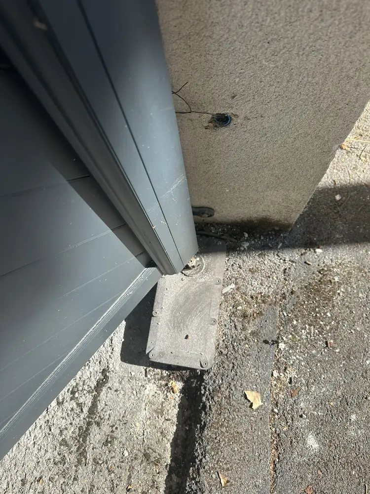 Bas de vantail d’un portail aluminium gris au ras du seuil