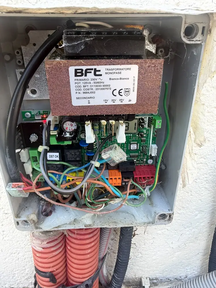 Boîtier de commande BFT ouvert sur un pilier de portail, carte et câblage