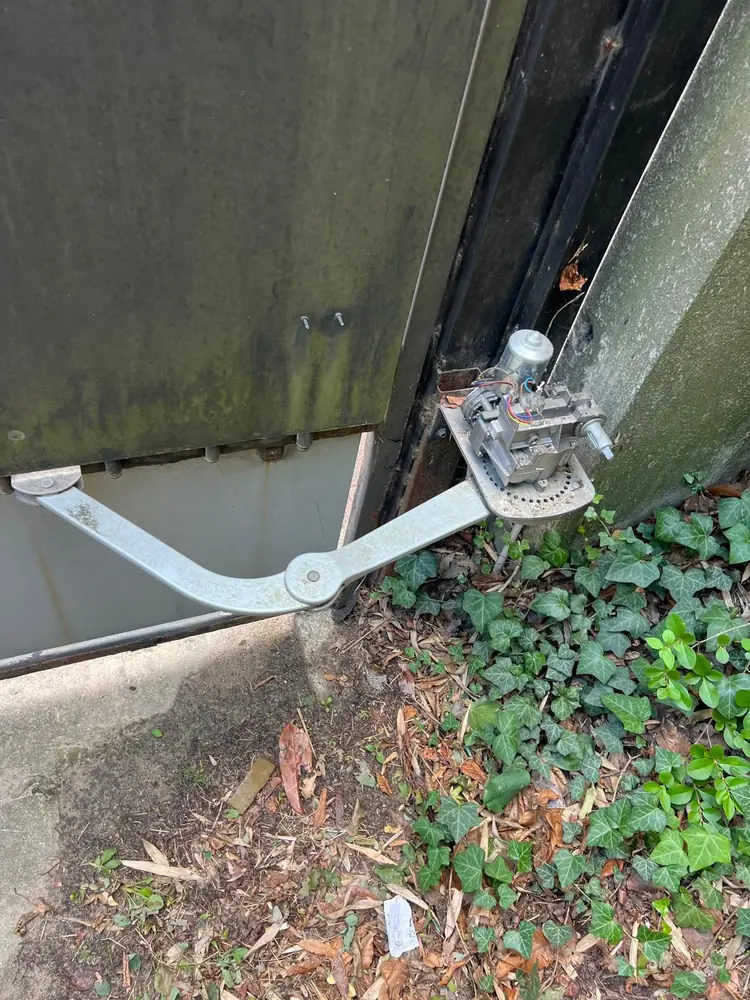 Bras articulé de motorisation fixé sur un portail noir