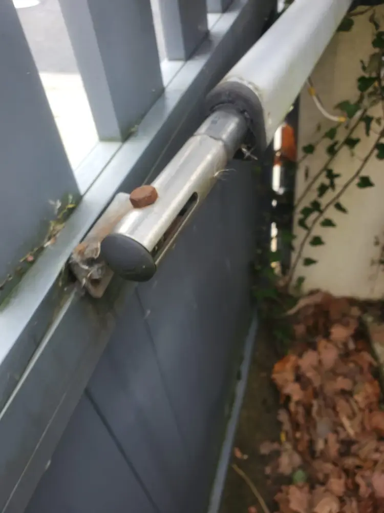 Bras de motorisation fixé sur un vantail gris