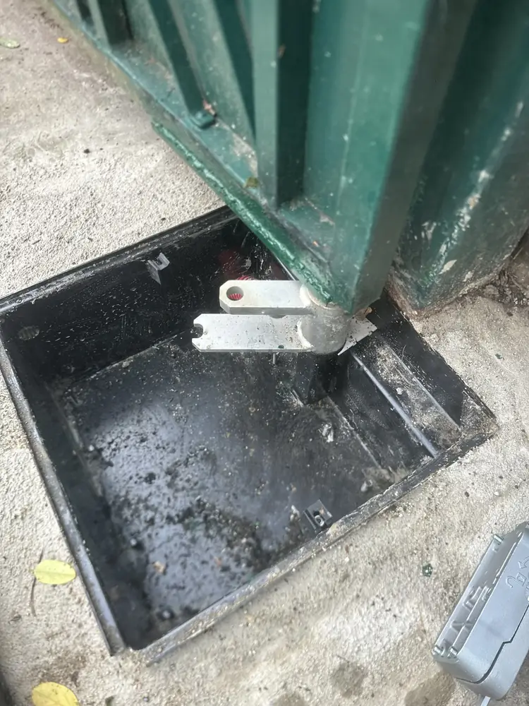 Butée et articulation au sol d’un portail battant, caisson ouvert pour réglage