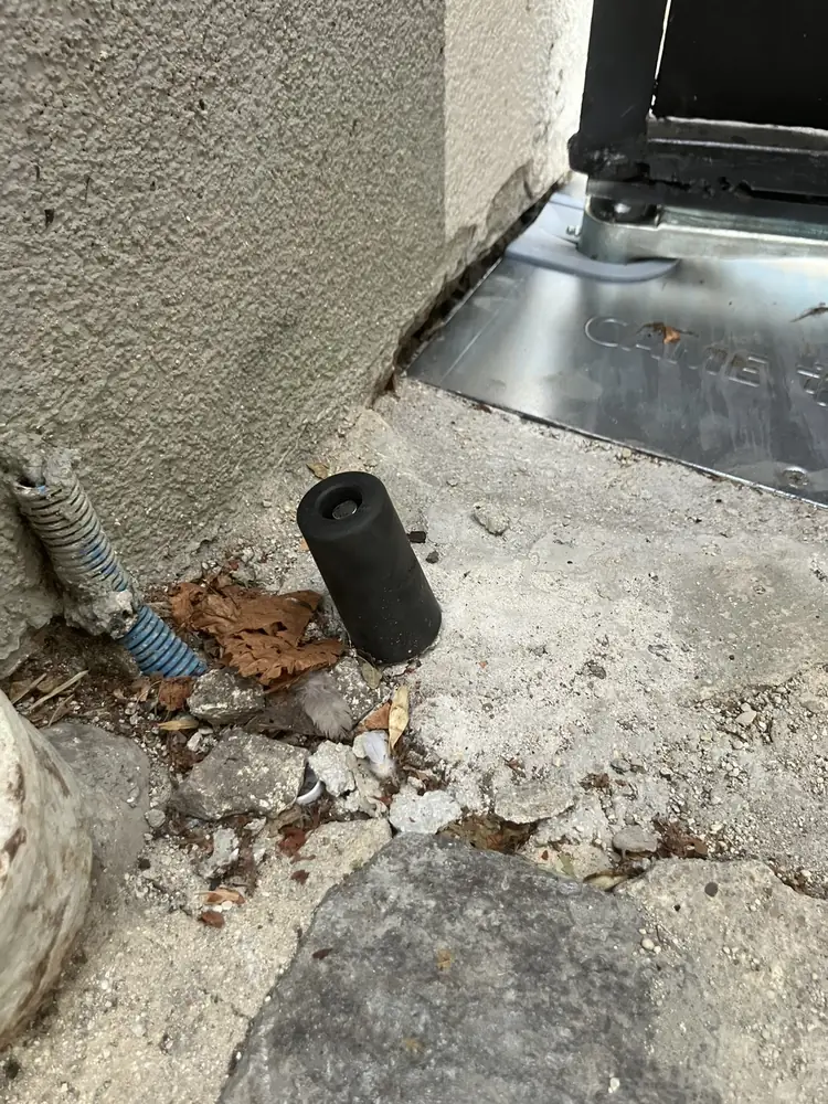 Butée au sol et gaine électrique d’un portail battant, au pied du pilier