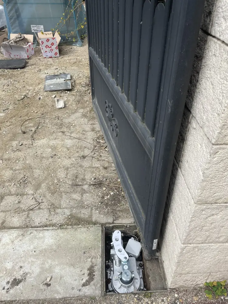 Caisson de moteur enterré ouvert au pied d’un vantail anthracite
