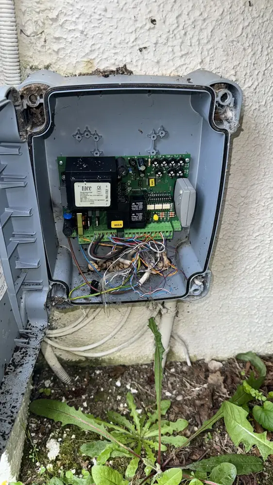 Coffret de commande de portail ouvert sur un mur crépi