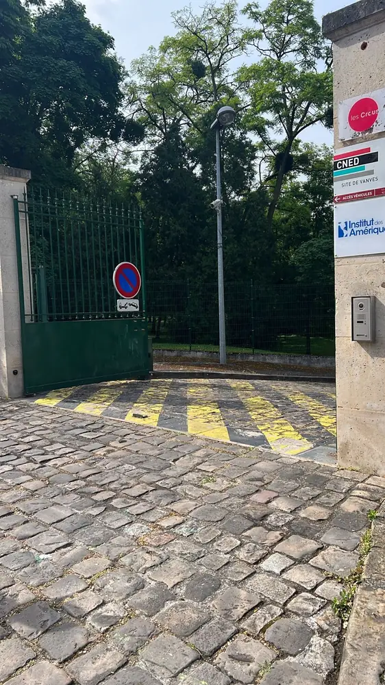 Entrée d’établissement : portail vert et interphone sur pilier béton