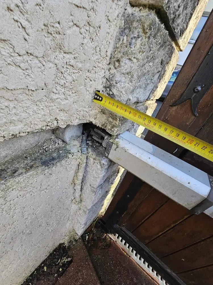 Fixation d’un vérin sur le pilier d’un portail en bois