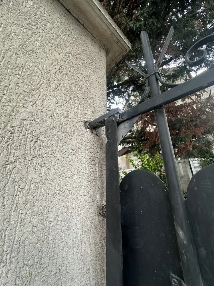 Gond haut d’un portail en fer forgé scellé dans un pilier