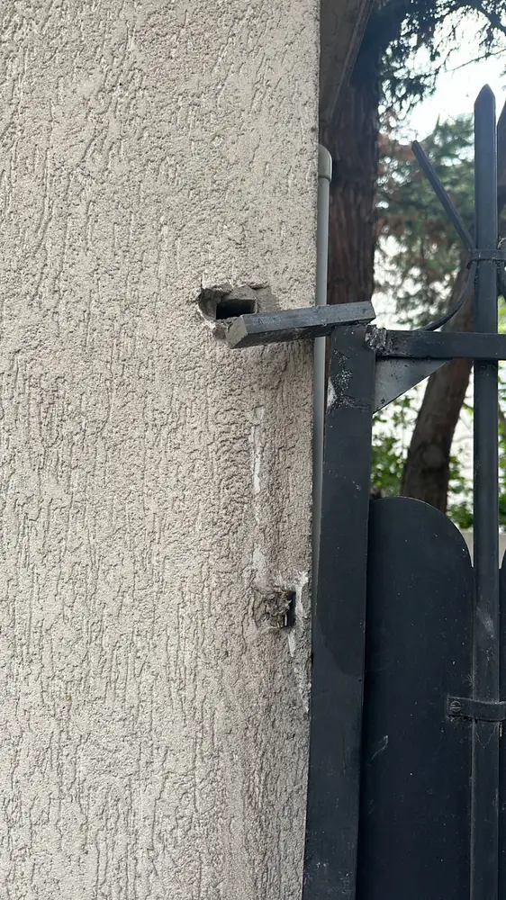 Gond scellé dans un pilier crépi, vantail en fer noir