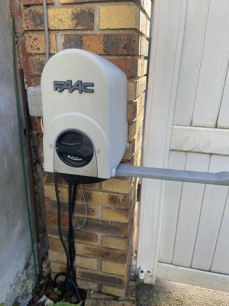 Moteur à bras FAAC fixé sur un pilier en brique d’un portail battant
