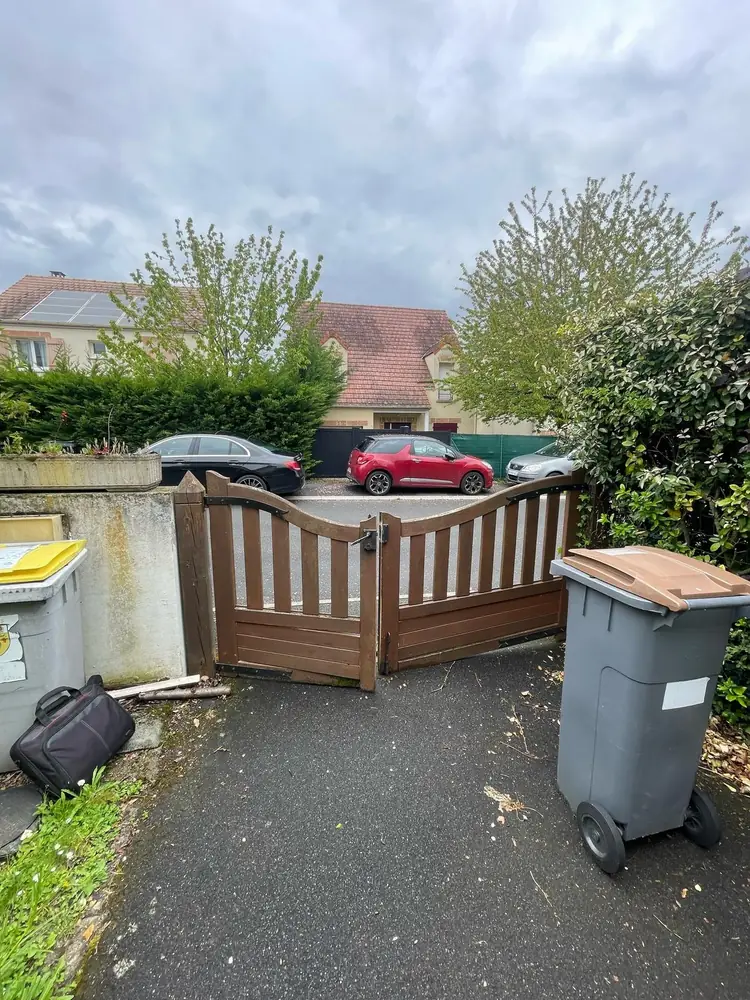 Portail battant en bois d’un pavillon vu depuis la rue : le bois demande un entretien régulier et des ferrures surdimensionnées