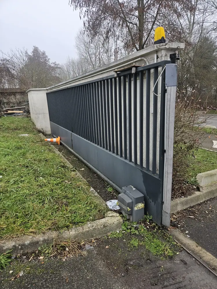Portail coulissant aluminium gris sur rail, moteur et feu clignotant en place