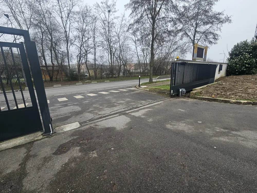 Portail coulissant noir ouvert sur une voie de desserte