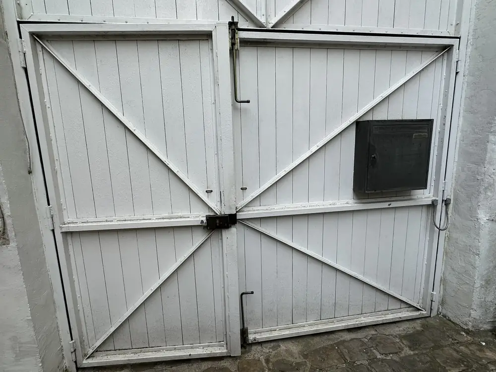 Porte de garage battante en bois blanc, boîtier de commande sur le vantail