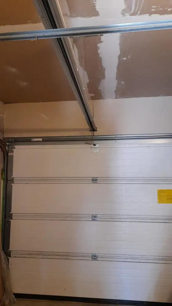 Porte sectionnelle à panneaux blancs sous un plafond incliné