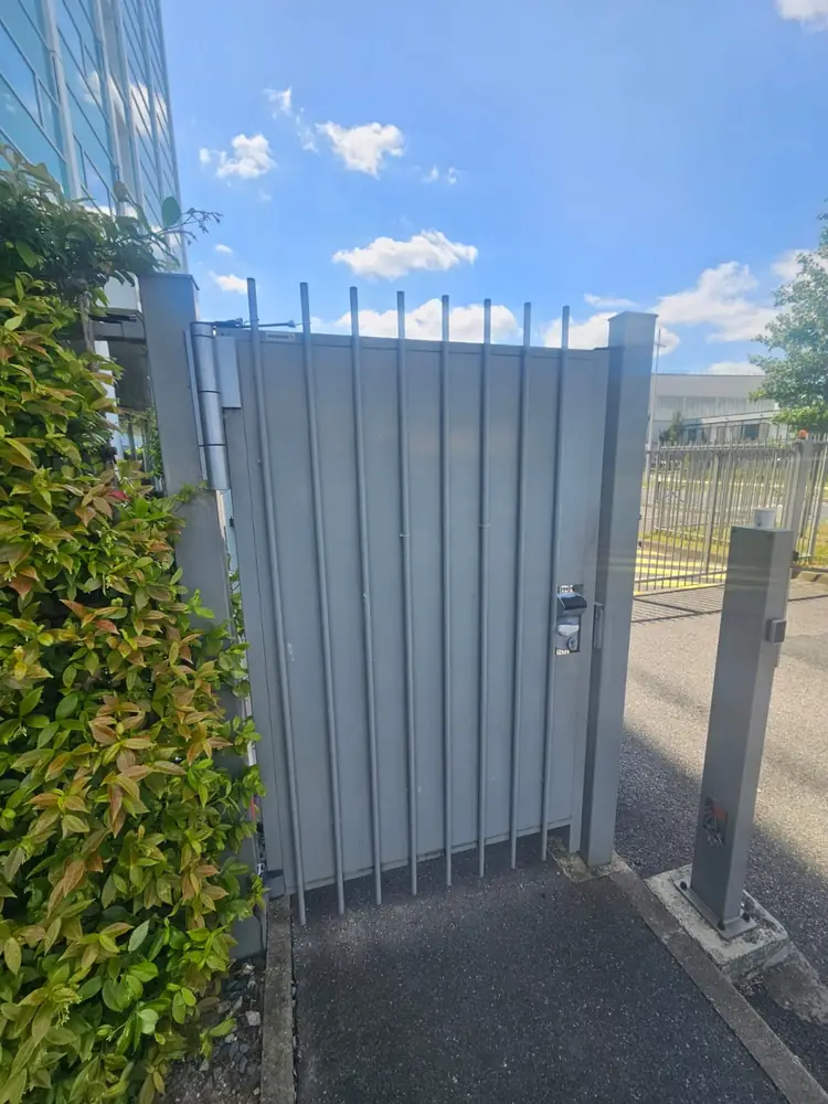 Portillon barreaudé motorisé à côté d’un portail coulissant d’entreprise