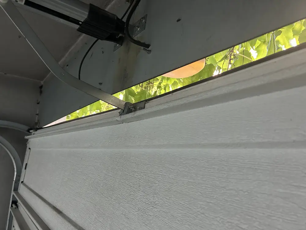 Rail et bras de motorisation au-dessus d’une porte sectionnelle