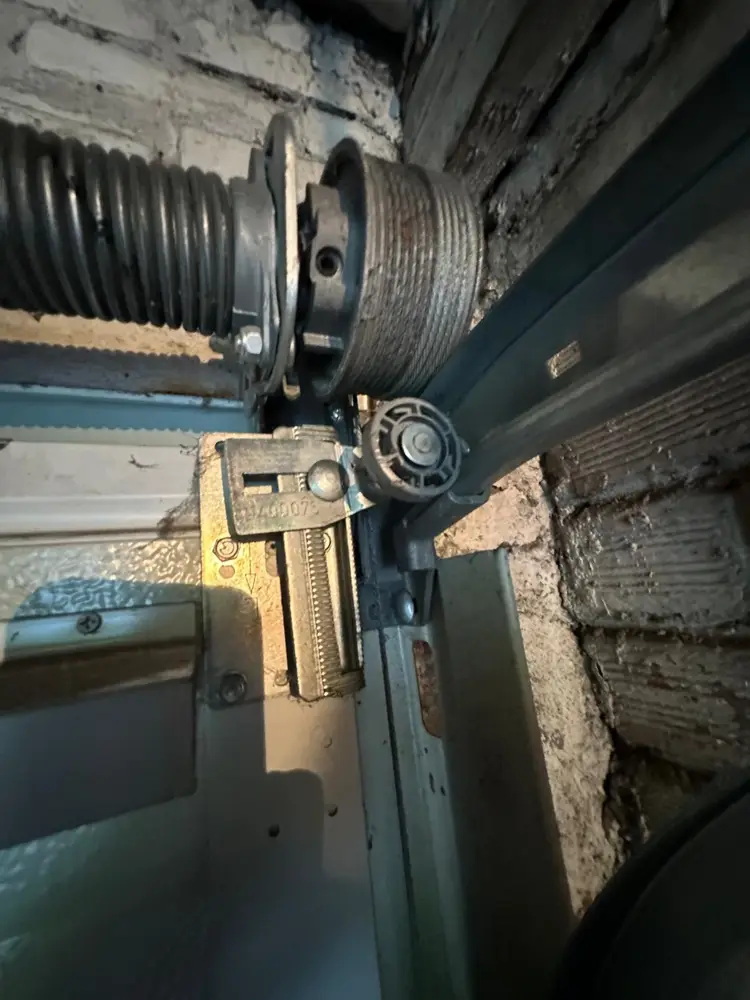 Ressort, tambour et câble d’une porte sectionnelle contre un mur ancien