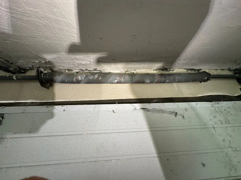 Ressort de torsion d’une porte sectionnelle sous le linteau