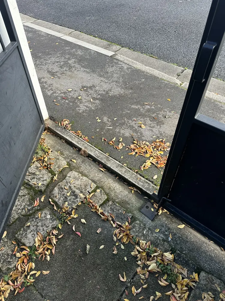 Seuil d’un portail coulissant : rail encombré de feuilles à nettoyer