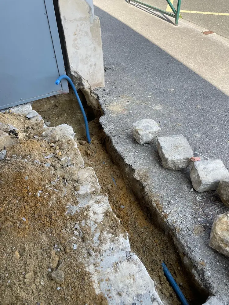 Tranchée le long du trottoir pour l’alimentation d’un portail