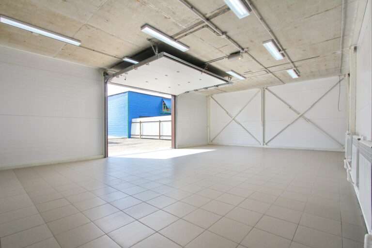 empty light parking garage, warehouse interior with large white gates and gray tile floor